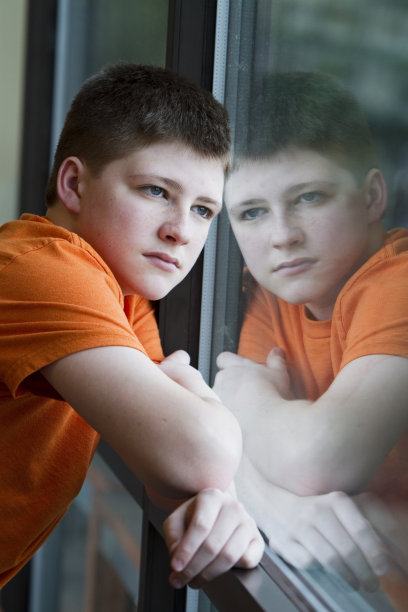 十几岁的男孩盯着窗外沉思图片下载