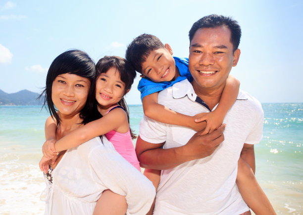 快乐的亚洲家庭在沙滩上看着镜头。图片下载