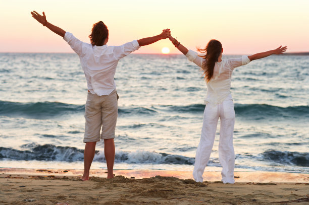 一对夫妇举起手臂看日落图片下载