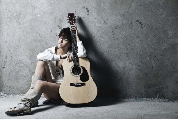 灰色的墙壁上，留着短发拿着吉他的女孩图片下载