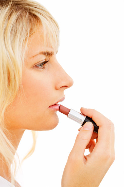 年轻的女孩在白色的背涂上红色的口红图片下载