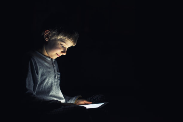 小男孩晚上在平板电脑上看书图片下载
