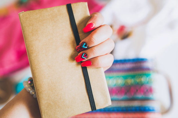 女性的手与时尚多彩的波西米亚指甲持有笔记素材图片