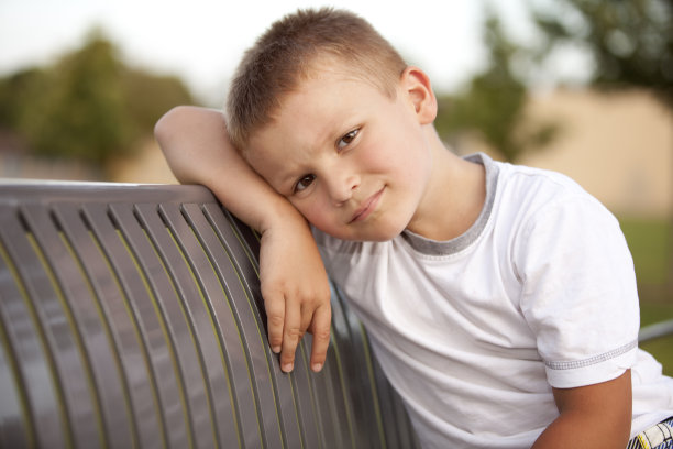 悲伤的小男孩独自坐在长凳上图片下载