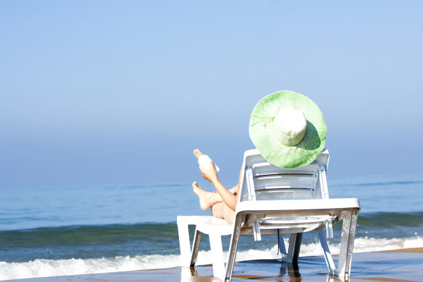 在海滩的日光浴床上晒太阳的漂亮女人图片下载
