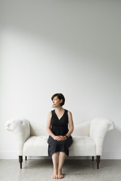 一个女人坐在白色房间的沙发上图片下载