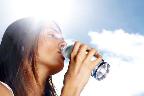 年轻女性在阳光明媚的日子里喝水图片下载