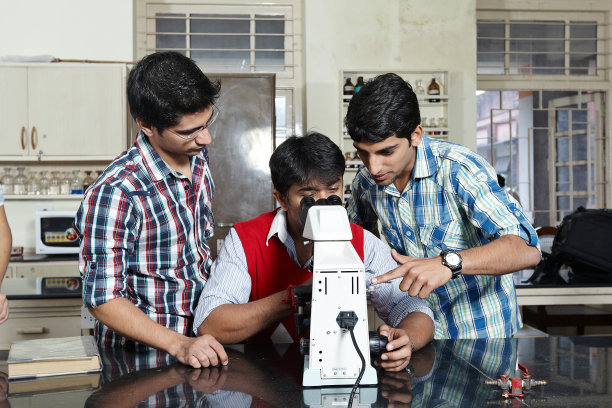 一名印度男学生在大学实验室里通过显微镜观察图片下载