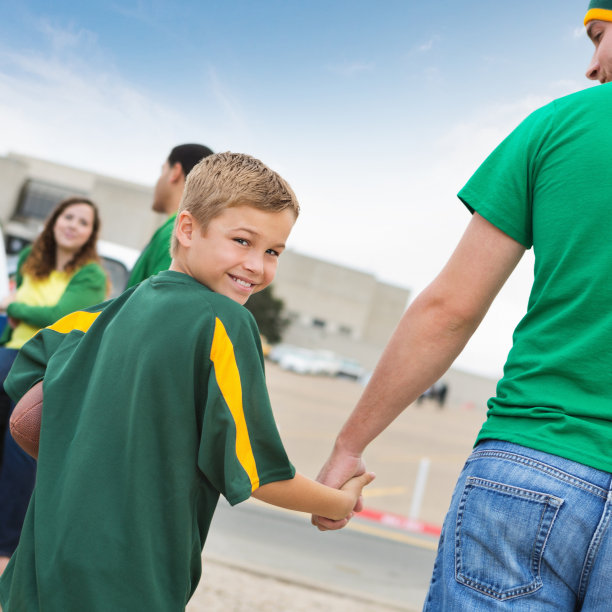 快乐的小男孩和爸爸在大学橄榄球场追车图片下载