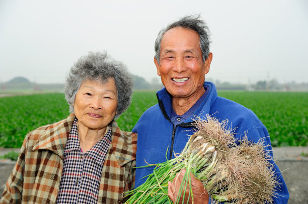 农夫夫妇微笑着拿着韭菜素材图片