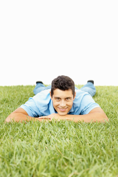 微笑的帅哥躺在草地上放松图片下载