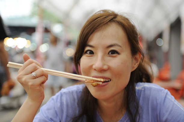 一个女人在户外咖啡馆享受亚洲食物图片下载