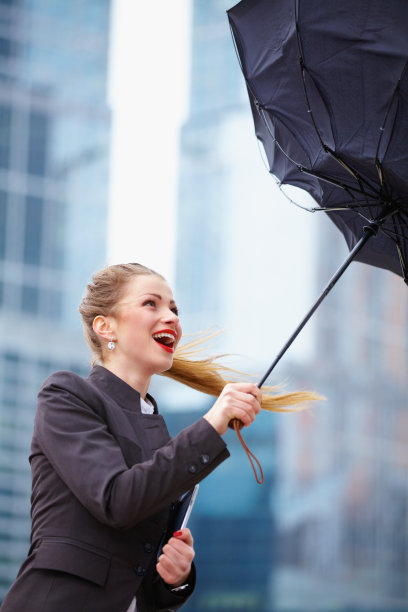 女人撑着伞对抗强风图片下载