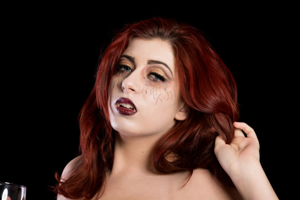 红发少年吸血鬼手握头发，拿着酒杯。图片下载