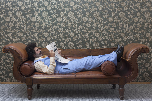 优雅的商人坐在沙发上看报纸图片下载