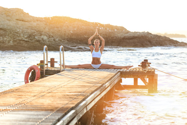 一个年轻女人在码头上练瑜伽图片下载