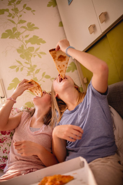 少女们在床上吃着大块披萨图片下载