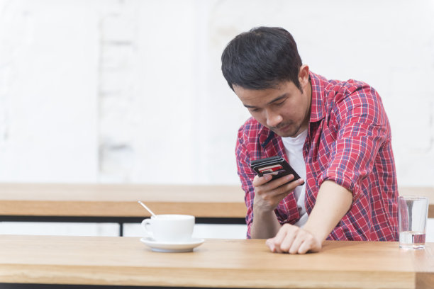 年轻的亚洲男子在咖啡馆使用电话图片下载
