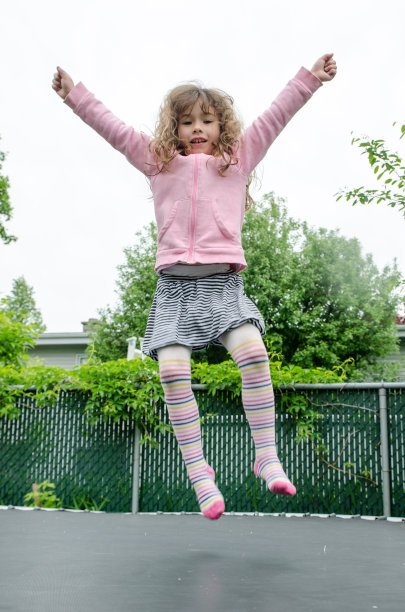 小女孩在后院蹦床上跳图片下载