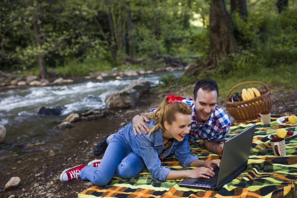 情侣在河边的自然环境中用笔记本电脑图片下载