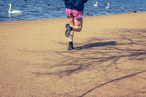 年轻人在公园的湖边跑步图片下载