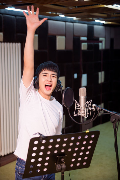 一个年轻的歌手在录音室录制一个轨道的特写素材图片