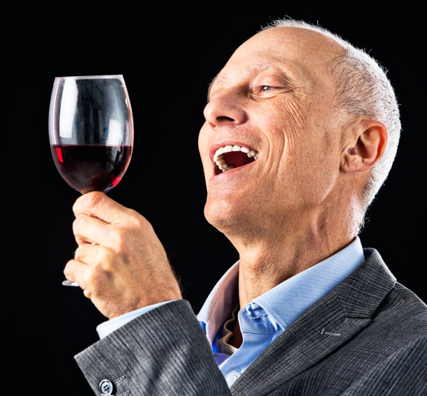 成熟的商人微笑着，举起一杯红酒图片下载