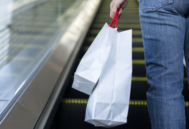 拿着购物袋的女孩，站在自动扶梯上图片下载