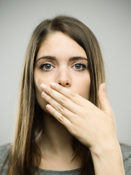 年轻的女人用手捂着嘴图片下载