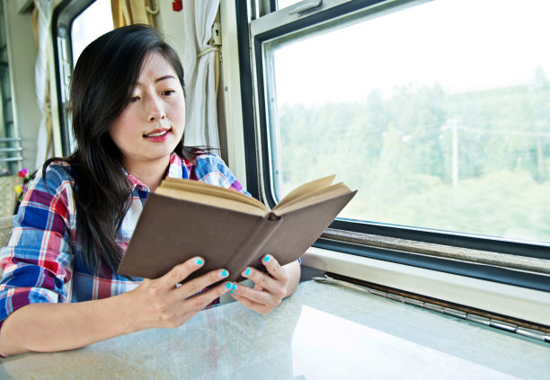 一个年轻的亚洲女人在火车上看书图片下载