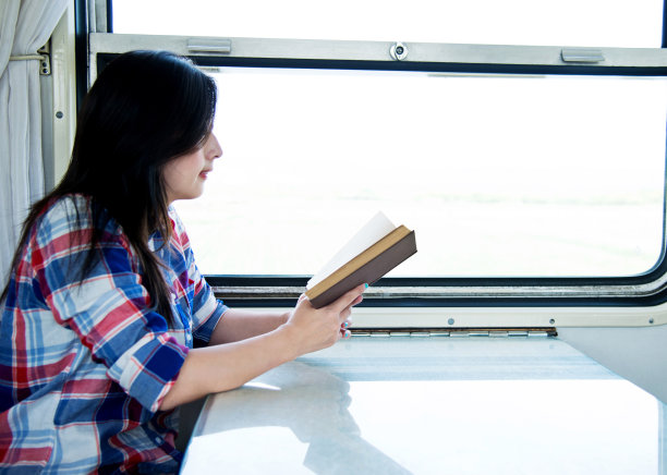 一个年轻的亚洲女人在火车上看书图片下载