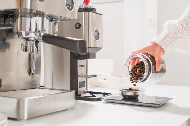 女士将咖啡豆倒在称重容器里的手图片下载
