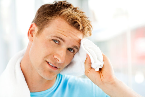 疲惫的男人在健身房清理脸上的汗水图片下载