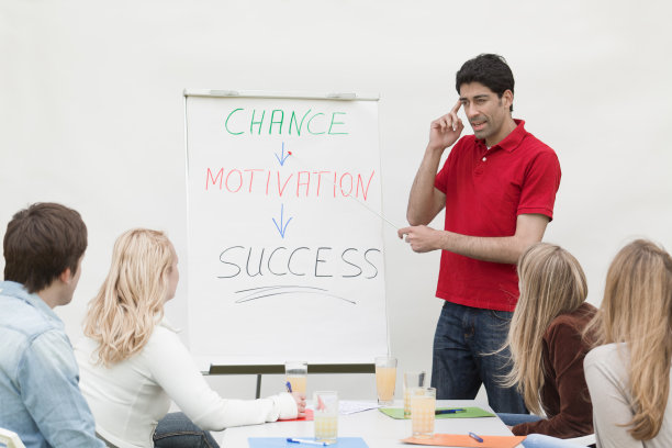 男实习生在白板上与一群学生交谈图片下载