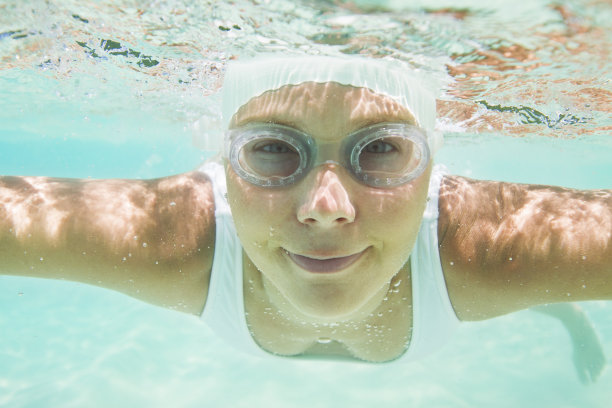 戴着游泳帽和护目镜潜水的女人图片下载