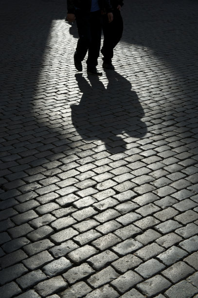 两个人走在阴影鹅卵石街上图片下载