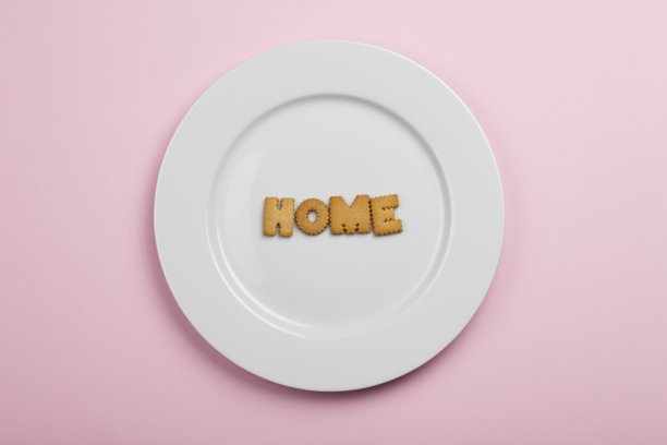 白色盘子上有饼干字母“家”粉红色的背景图片下载