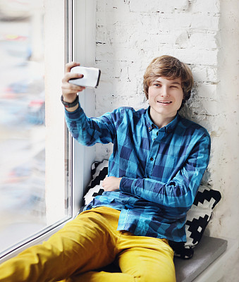 一个少年坐在窗台上拿着手机图片下载
