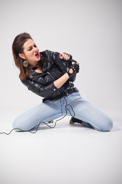 年轻女歌手跪着对着麦克风唱歌图片下载