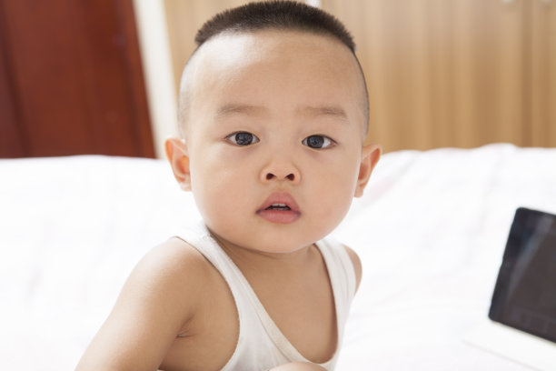 小男孩拿着平板电脑坐在床上图片下载