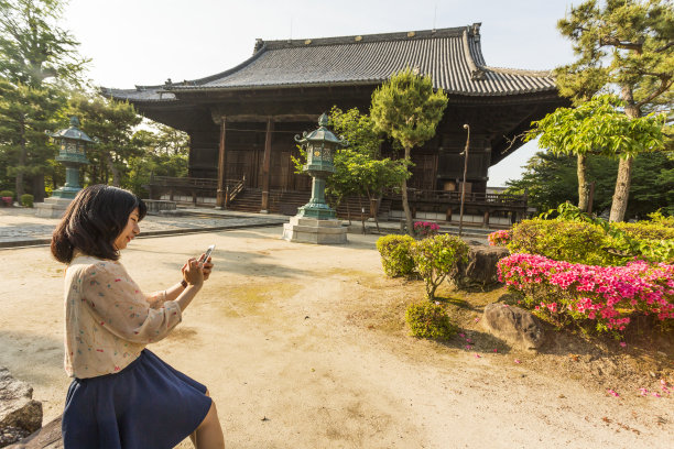 一名日本妇女在一座佛教寺庙里使用手机图片下载