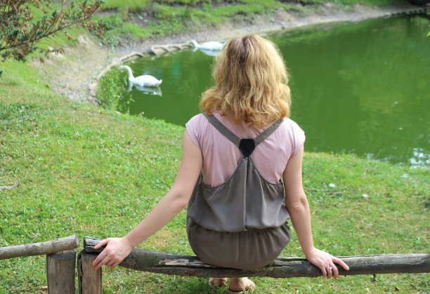 和天鹅在池塘前的女人。图片下载