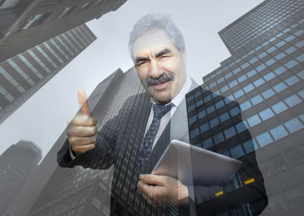 带着平板电脑微笑的资深商人的肖像，映衬着摩天大楼图片下载