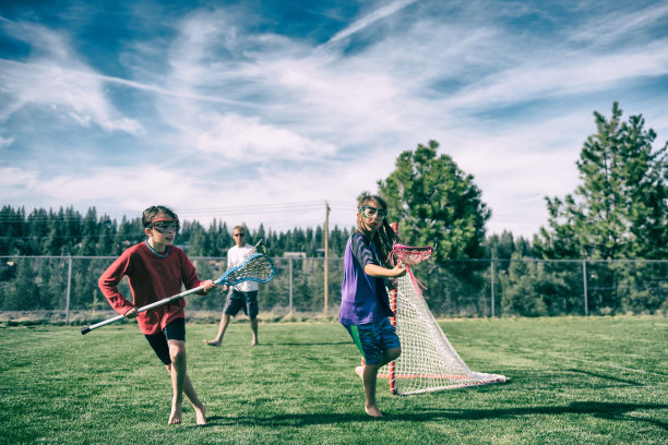 在爸爸的注视下，女孩们在美丽的田野里打曲棍球图片下载