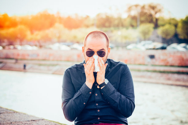 年轻的商人在城市的街道上擤鼻涕图片下载