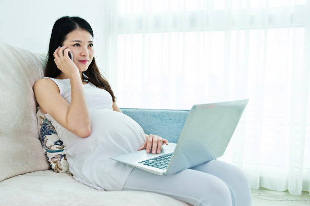 孕妇坐在沙发上使用笔记本电脑素材图片