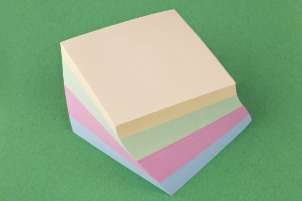 便利贴，黄色，绿色，粉色和蓝色在绿色的纸的背景图片下载