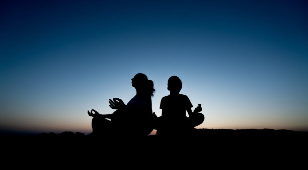 母亲和孩子们在夕阳下做瑜伽的剪影图片下载