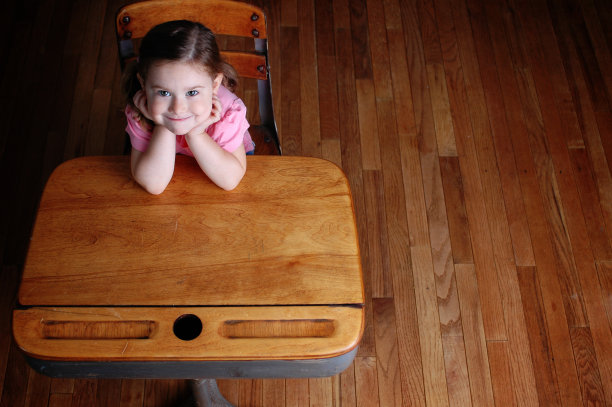 快乐的小女孩坐在课桌上图片下载