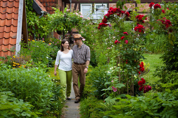 一对夫妇在鲜花盛开的农家花园里散步图片下载